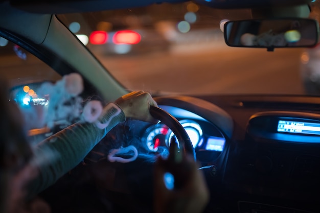 The man make a smoke rings in the car. Evening night time