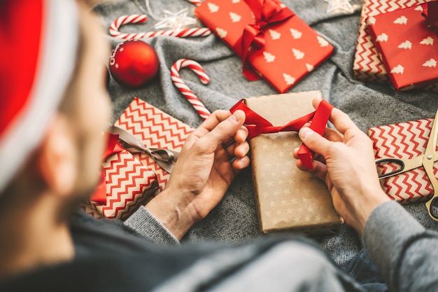 Man making bow from ribbon on gift