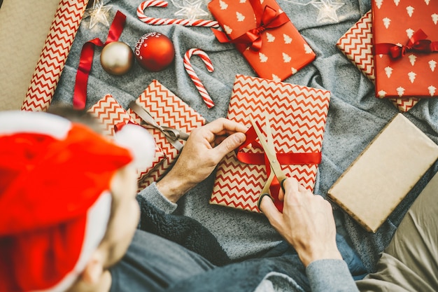 Man making bow from ribbon on gift