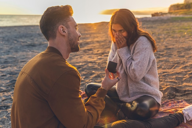 Man making proposal to woman on sandy sea shore