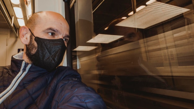 Man in mask looks out window of moving train