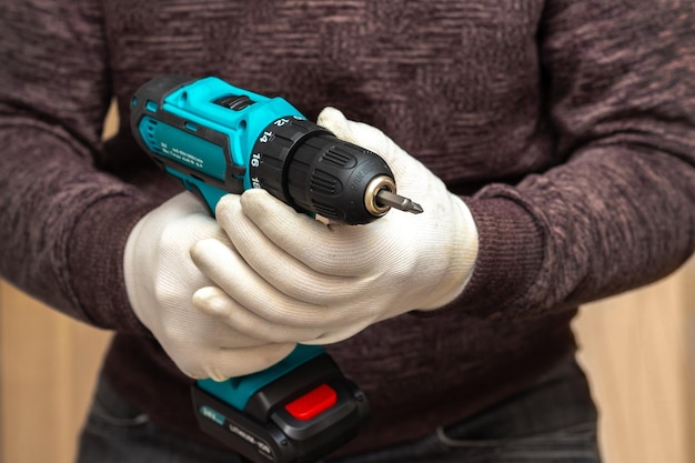 Photo man master holds a cordless screwdriver to tighten the screws