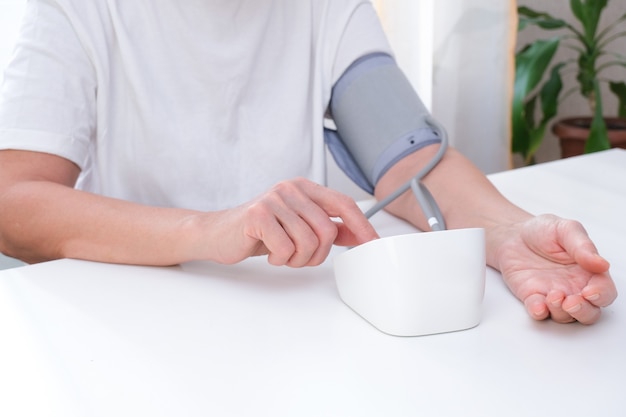 Man measures blood pressure, white background. arterial hypotension. hand and tonometer close up.