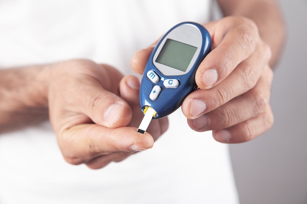 Man measuring glucose level at home.