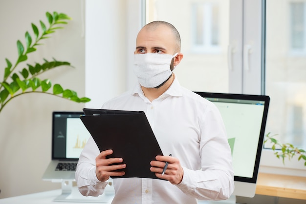 Man in medical mask holding a pen and a folder