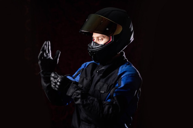 man in a motorcycle helmet in an outfit on a dark studio background.