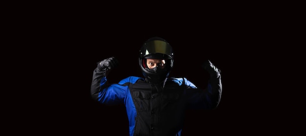 man in a motorcycle helmet in an outfit on a dark studio background.