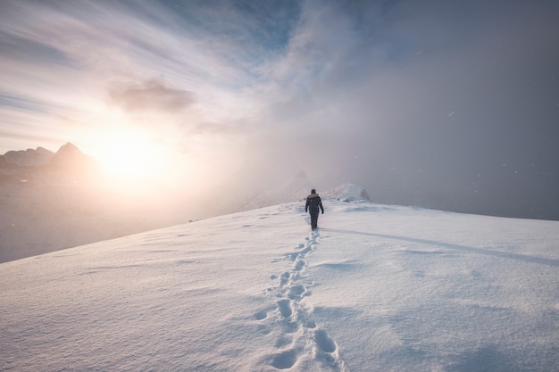 Man mountaineer walking with snow footprint on peak ridge