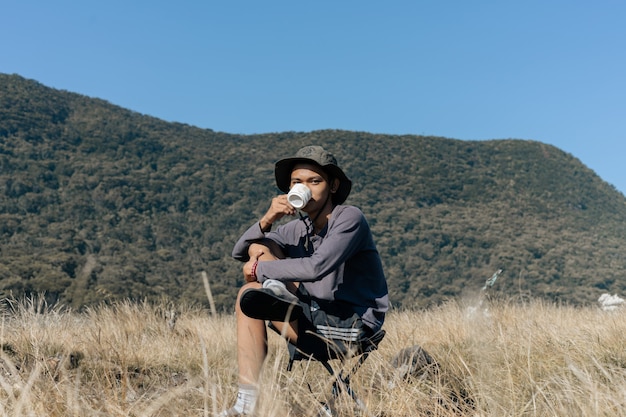 A man in the mountains drinking from a cup