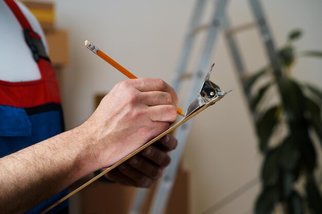 Man mover in uniform making notes on clipboard close up