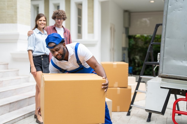 Photo man mover worker in blue uniform unloading cardboard boxes from truck