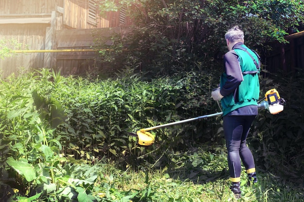 Man mows and cuts the grass with a gasoline trimmer in the garden Mows tall grass