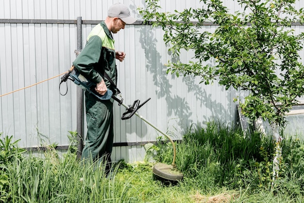 A man mows lawn grass with a lawn mower petrol lawn mower trimmer closeup Man working in the garden