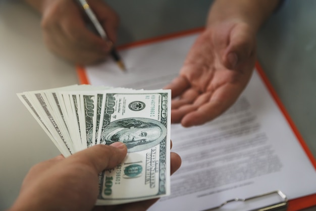 Man offering batch of hundred dollar bills.