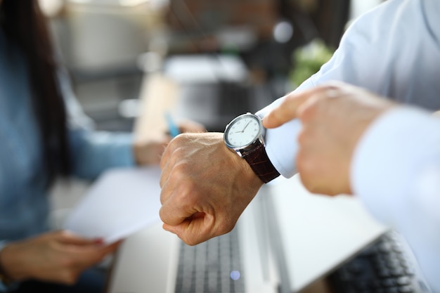 Man in office shows a finger at clock