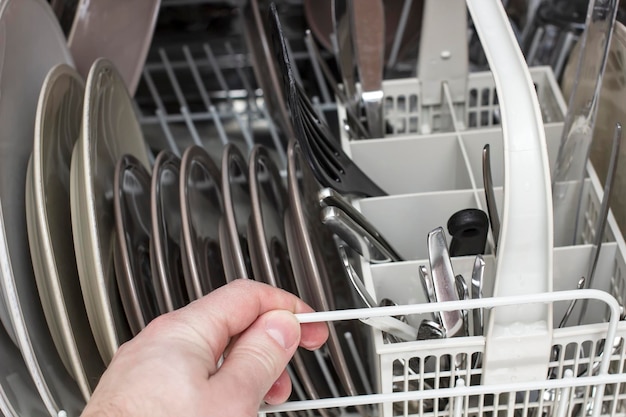 Man opened the dishwasher with his hand and was going to get perfectly clean dishes after washing