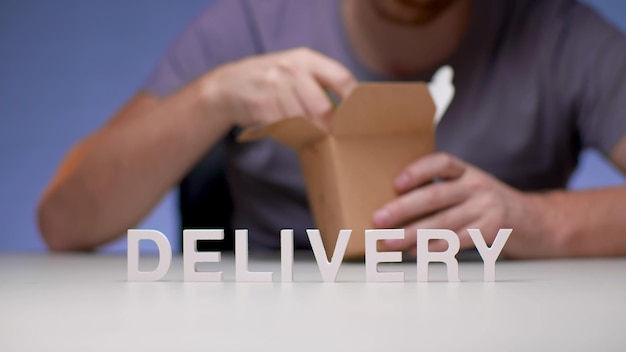 Photo a man opening a brown box with the word delivery on it