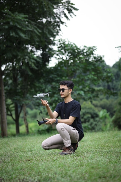 A man operating the drone by remote control in the greeny park Drone pilot