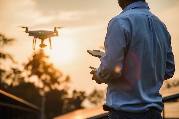 Man operating a drone with remote control, drone pilotage at sunset