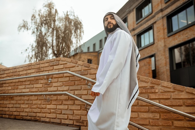 A man outside An arabian man in white traditional clothing on the stairs