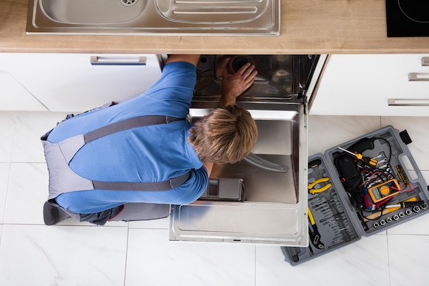 Man In Overall Repairing Dishwasher