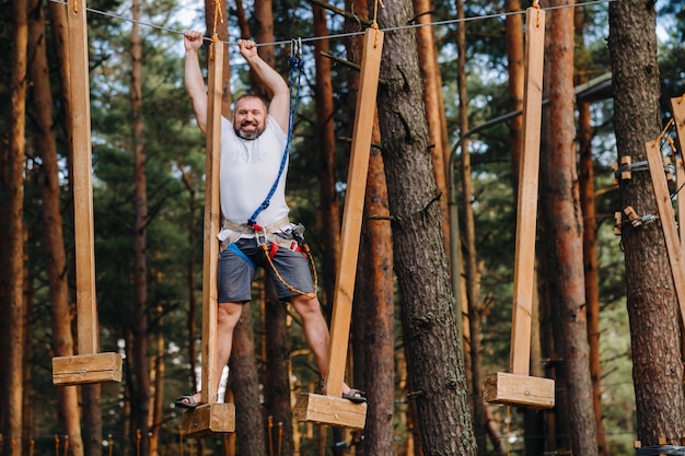 A man overcomes an obstacle in a rope town A man in a forest rope park