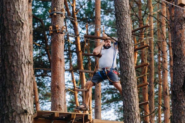 A man overcomes an obstacle in a rope town A man in a forest rope park