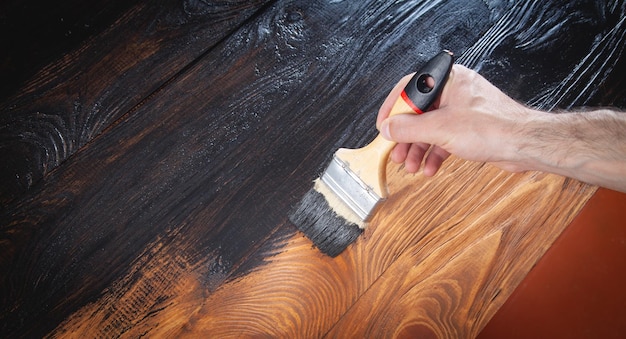 Man painting wood with a brush