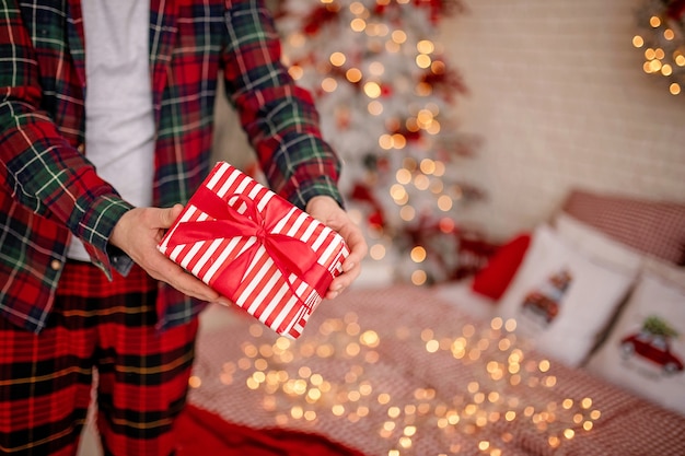 man in pajamas holding a christmas present