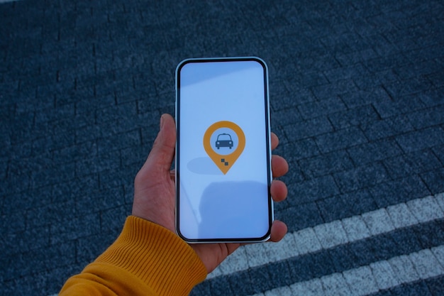 Man passenger in the parking lot holds a smartphone with a mobile application and calls a taxi online.