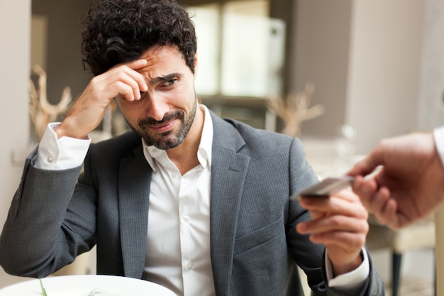 Man paying the bill with a credit card and feeling bad because the sum is too high