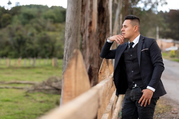 Man pensive against a fence of a Latino farm. Looking into the distance. Copy space