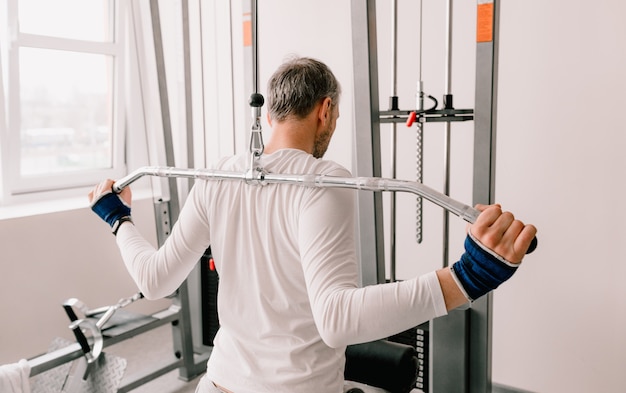 A man performs exercises in the gym on a simulator. back training. rear view