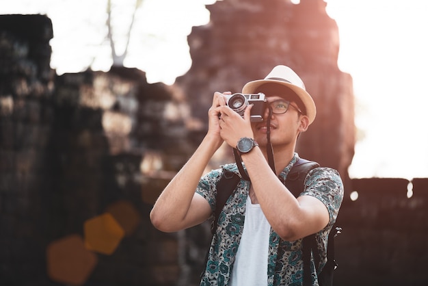 Man Photographer Traveler with backpack taking photo with his retro film camera