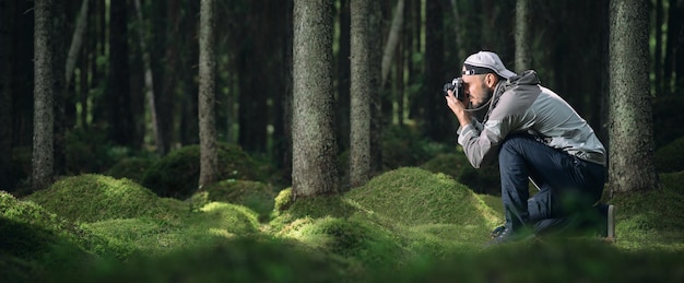 Photo man photographing by tree trunk in forest