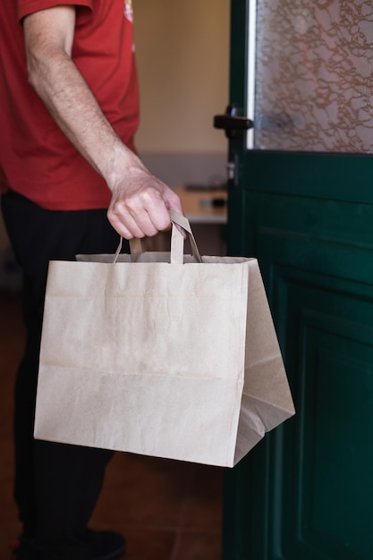 Man picking up a bag from the door of his house Online shopping Home delivery Vertical photo