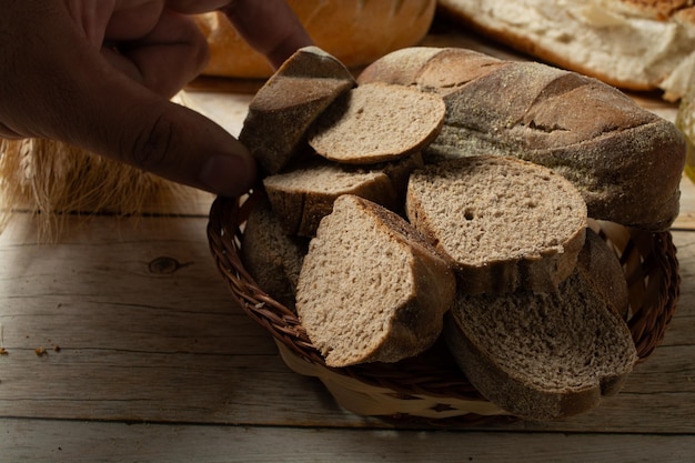 man picking up slices of dark bread on a basket also known as australian bread