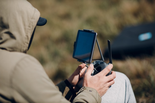 Man pilot controlling quadcopter drone with remote controller pad.