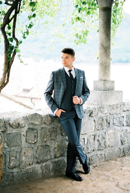 Man in a plaid suit stands in a stone gazebo in the garden