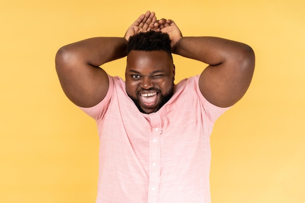 Man playfully showing bunny ears winking to camera laughing and humorous expression