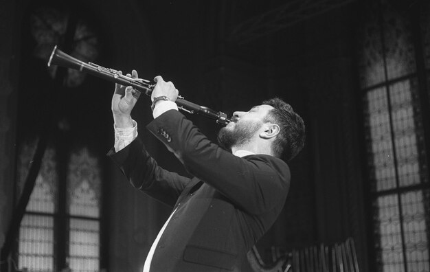 Photo man playing clarinet while standing at studio