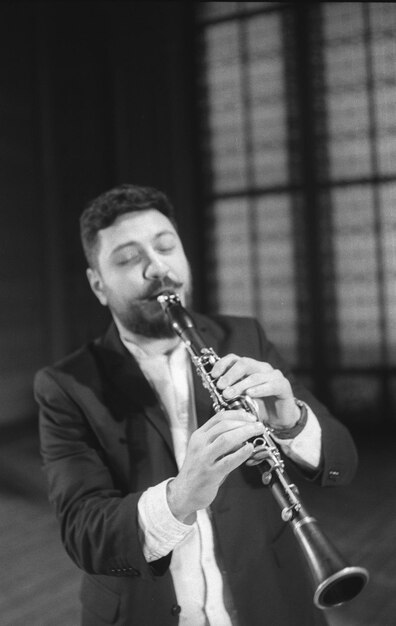 Photo man playing clarinet while standing at studio