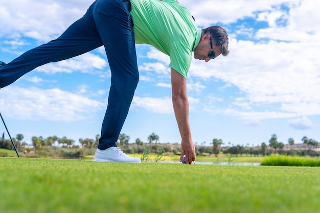 Man playing golf at golf club by a lake putting the ball