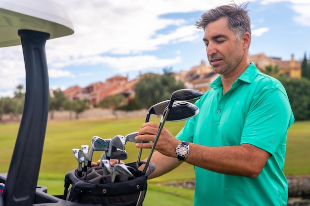 Man playing golf at golf club checking golf clubs before hitting the ball