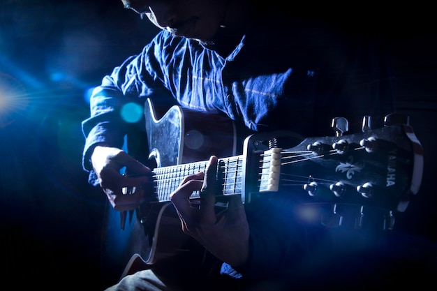 a man playing a guitar blue background optical flair