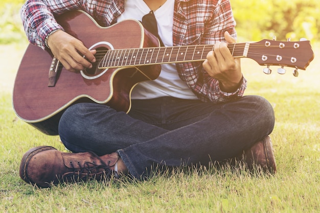 Man playing guitar, sitting on green grass