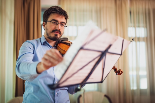 Photo man playing violin at home he is practicing for live performance