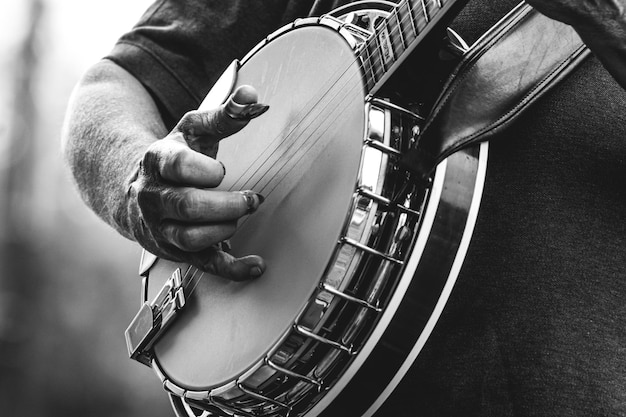 Photo a man plays a banjo with a gloved hand.