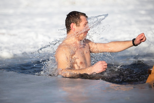 A man plunges into an ice-hole during the winter festival of the baptism of Jesus. A man swims in the ice-hole in winter. Walrus people.