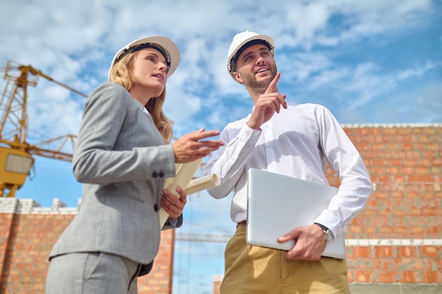 Man pointing hand up and looking woman